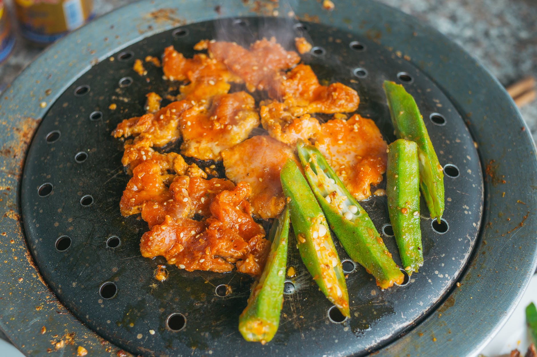 marinated pork and slices of okra on a griller