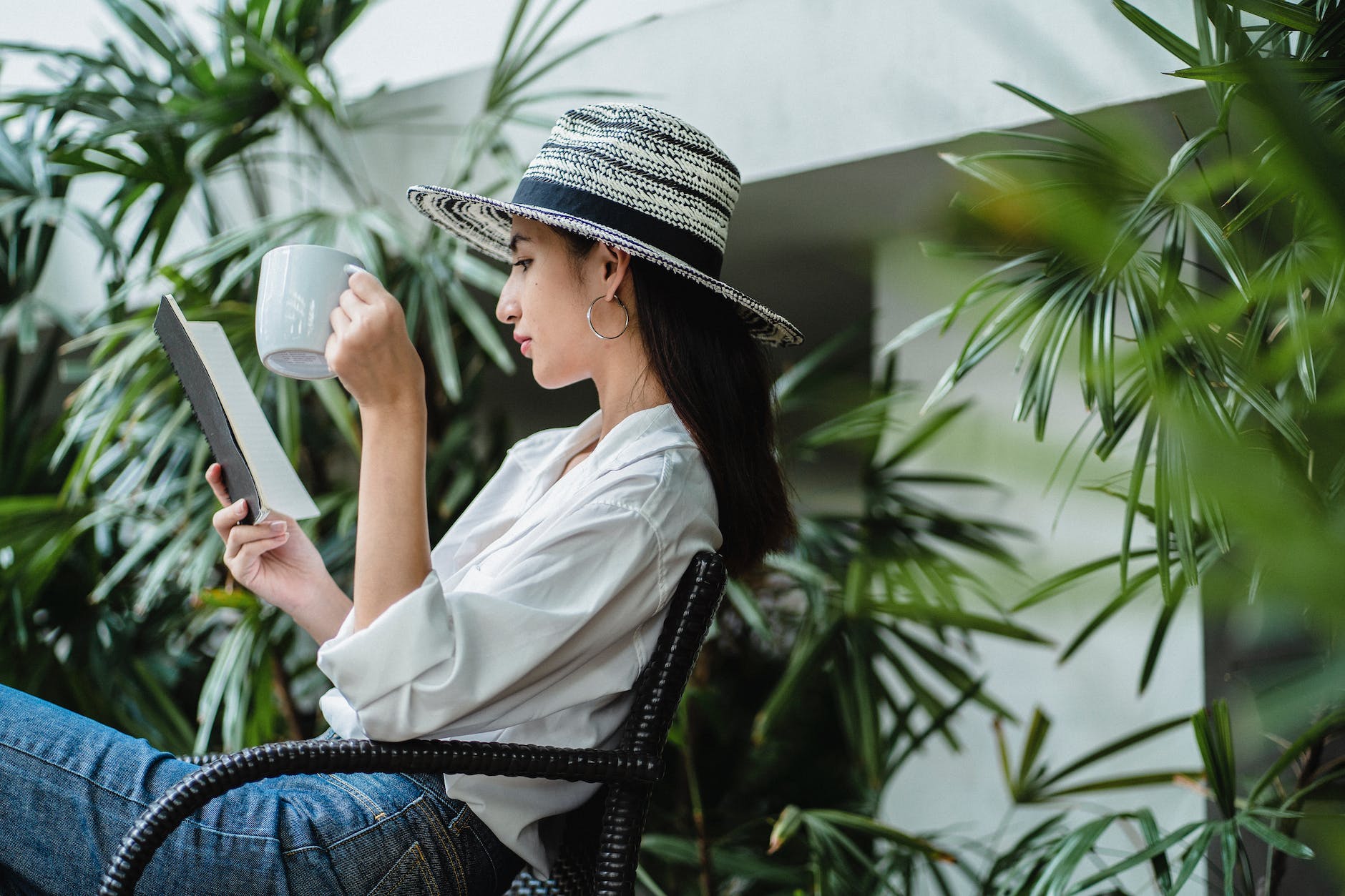 thoughtful young woman reading book and drinking beverage